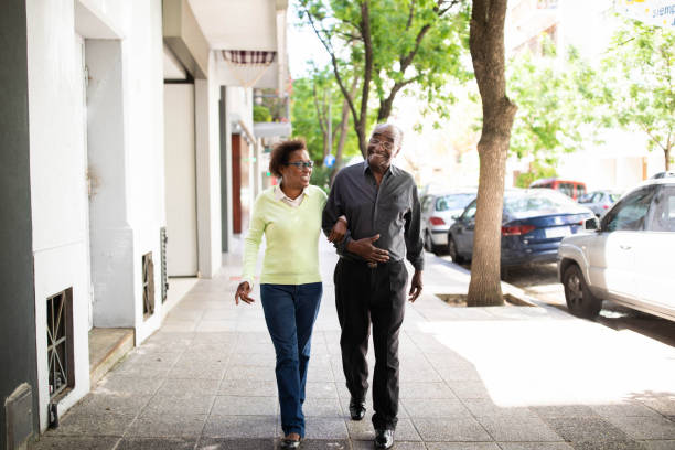 casal de idosos caminhando juntos em uma calçada - discussion mature adult senior adult couple - fotografias e filmes do acervo