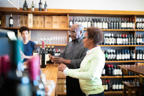 pareja senior comprando vino en una bodega - wine cellar liquor store wine rack fotografías e imágenes de stock