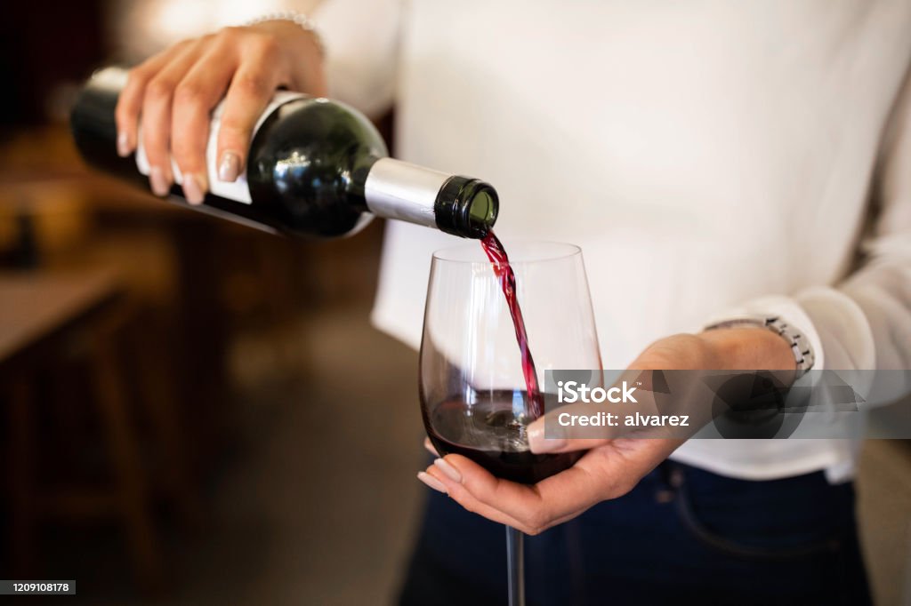 Mujer sirviendo vino tinto en una bodega - Foto de stock de Vino libre de derechos