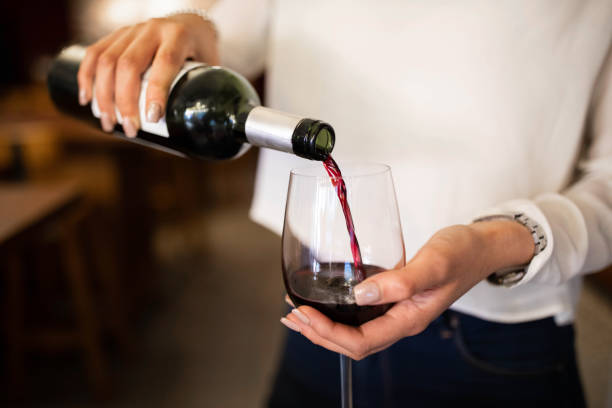Woman serving red wine in a winery Close-up of a woman hand pouring wine into a glass. Female waiter serving red wine in a winery. alcohol stock pictures, royalty-free photos & images