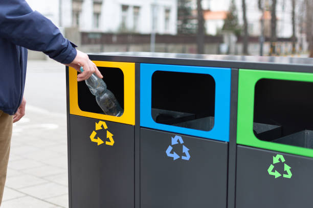 istock Hand of man throwing plactic bottle into trash bin for plastic waste. Modern colorful refuse bins for separate trash. 1209108647