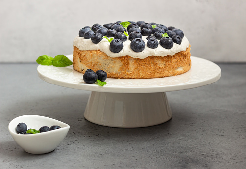 Angel food cake with whipped cream, fresh blueberries and basil.