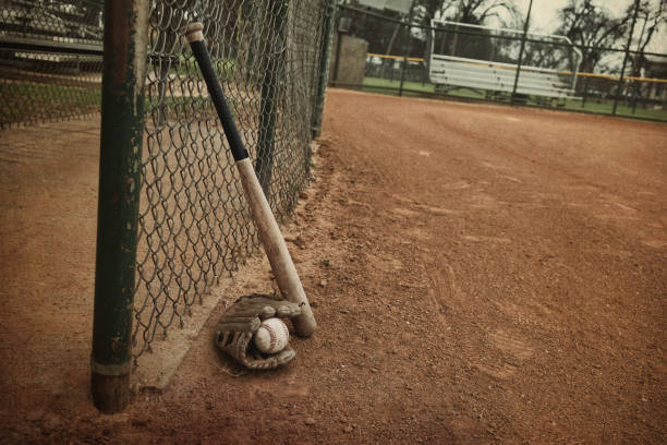 istock Baseball equipment leans on field fence 1209109538