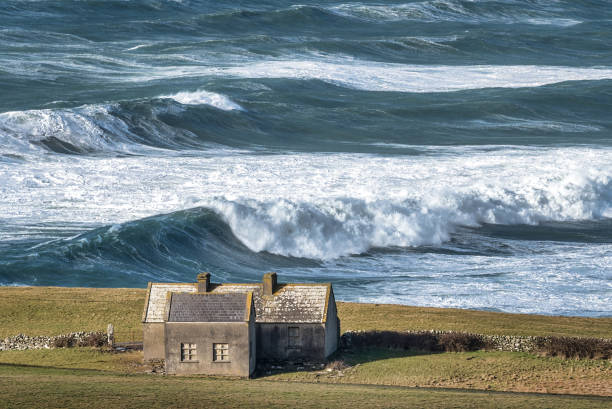Rough Sea and a Lonely Cottage Rough sea with large waves on the Irish coastline in County Clare near the Cliffs of Moher county clare stock pictures, royalty-free photos & images