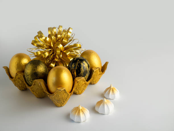 istock Easter eggs painted in gold and black in a textured stand on a white background with meringues 1209114779