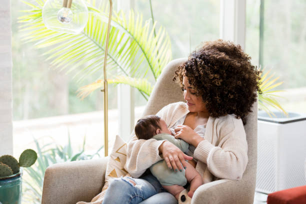 Mom breastfeeds newborn baby Young mom nurses her newborn baby while in the child's nursery. breastfeeding photos stock pictures, royalty-free photos & images