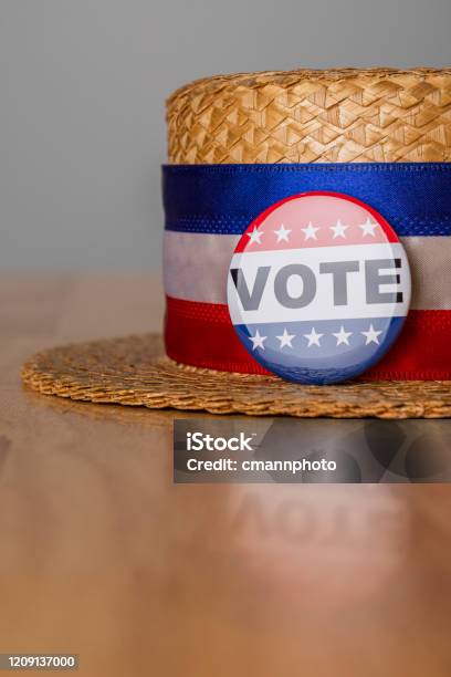 A Skimmer Hat With A Red White And Blue Head Band And A Vote Button Sitting On A Wood Table Stock Photo - Download Image Now