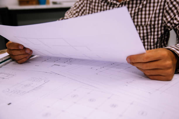 istock Close-up hand of male Architect drawing blueprint on work space in construction site. 1209146529