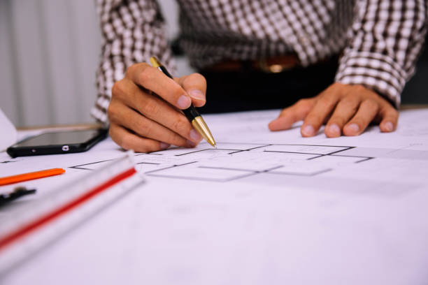 istock Close-up hand of male Architect drawing blueprint on work space in construction site. 1209146531