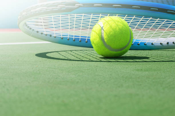 Tennis racket and tennis ball on court stock photo