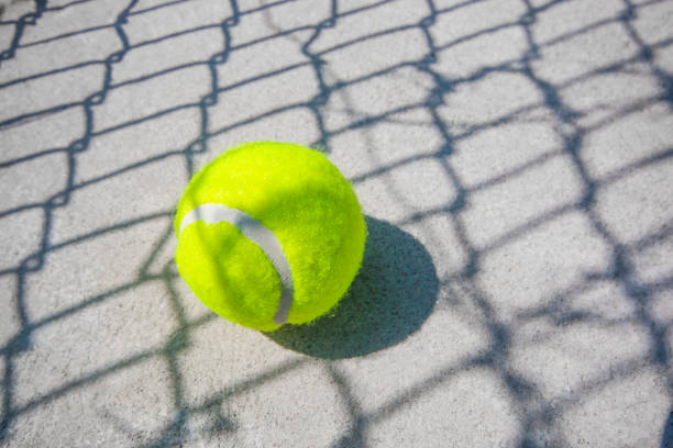 der tennisball wird auf den betonboden gelegt. es gibt einen schatten des netzes. - tpc sugarloaf stock-fotos und bilder