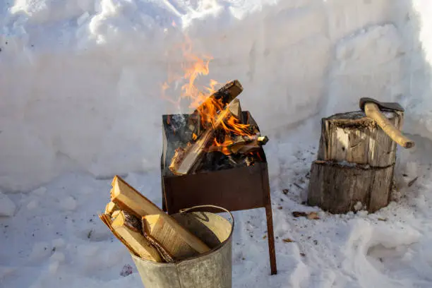 Photo of Barbecue with wood in winter on the street. Fry kebabs