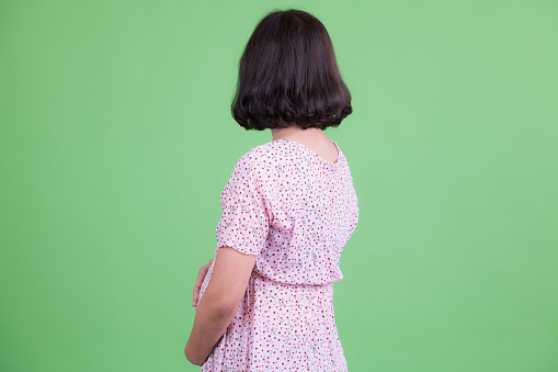 Studio shot of beautiful Asian pregnant woman with short hair against chroma key with green background