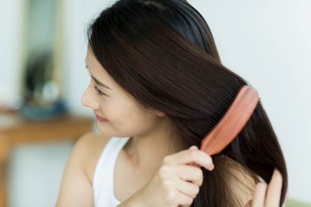 mujer joven cepillando el cabello - hair care combing women human hair fotografías e imágenes de stock