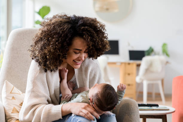 Happy mom plays with newborn son