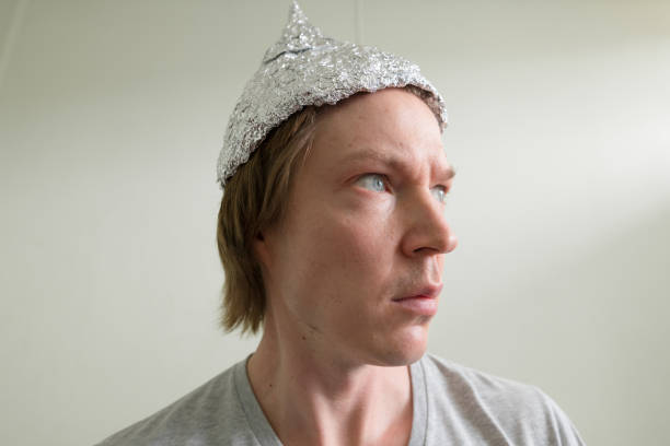 istock Face of young man with tin foil hat thinking inside the room 1209163022