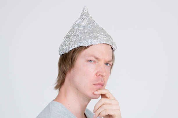istock Closeup profile view of young man with tinfoil hat thinking and looking at camera 1209163177