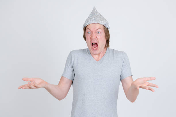 Studio shot of young handsome man wearing tin foil hat as conspiracy theory concept against white background