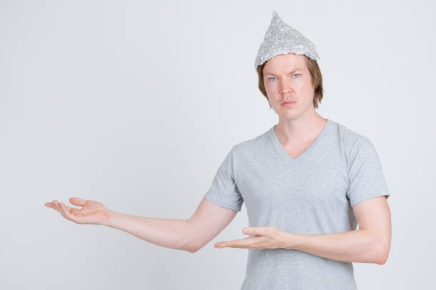 istock Young man with tinfoil hat as conspiracy theory concept showing something 1209163313