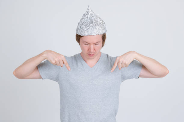 istock Young man with tin foil hat pointing and looking at shirt 1209163354
