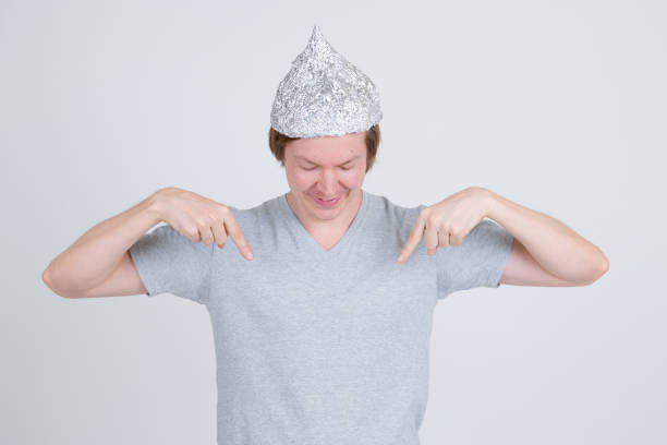 istock Happy young man with tin foil hat pointing and looking at shirt 1209163378