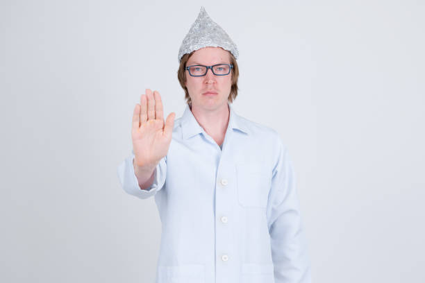 istock Serious young man doctor with tinfoil hat showing stop gesture 1209163666
