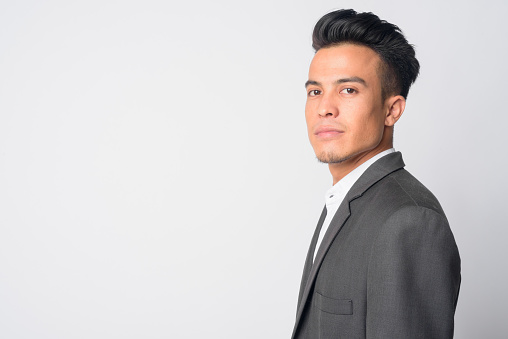 Studio shot of young Asian businessman in suit against white background