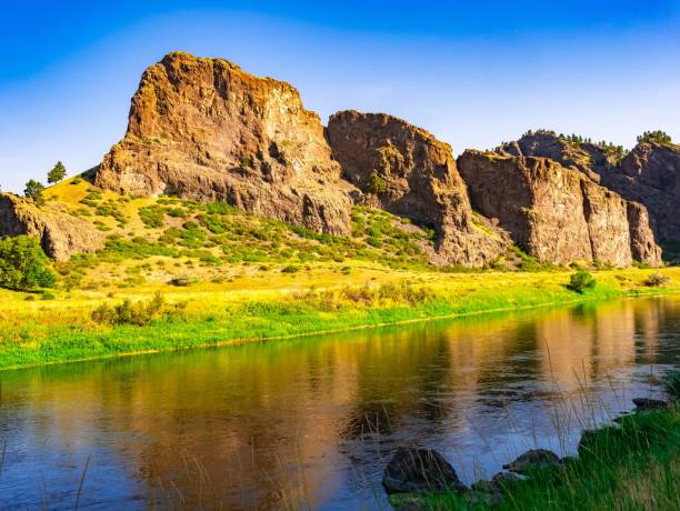 Reflecting Butte Three buttes reflections in a lake with green shore butte rocky outcrop stock pictures, royalty-free photos & images