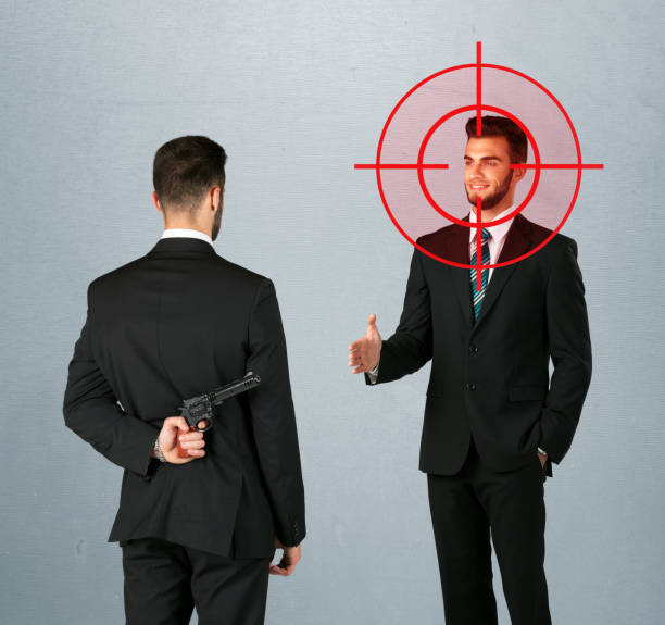 Angry business concept Ruthless businessman handshake with a hiding weapon and a head target point opposite nasty stock pictures, royalty-free photos & images