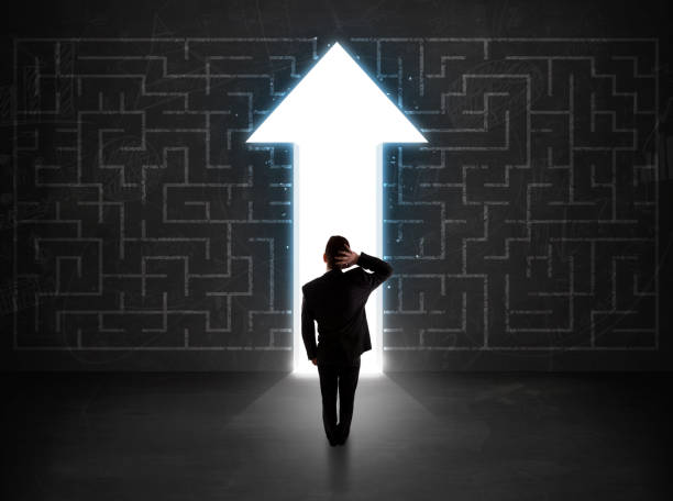 istock Business person looking at maze with solution arrow on the wall 1209179786