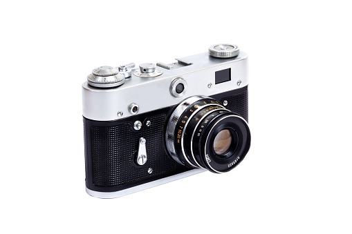 A rangefinder classic camera placed on reflective material. Dark backdrop.