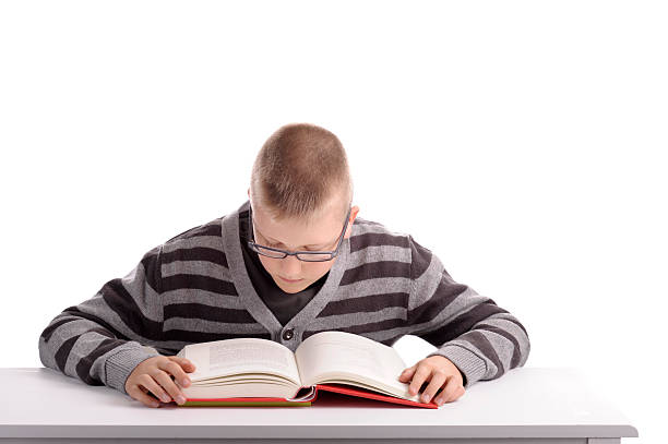 istock boy reading a book at his desk 120918358