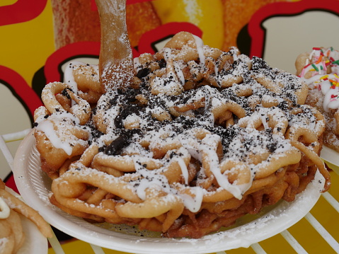 Close up of a chocolate caramel-flavored funnel cake with colored candy toppings