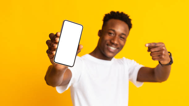 istock Happy african guy point at cellphone with white copy space 1209184768