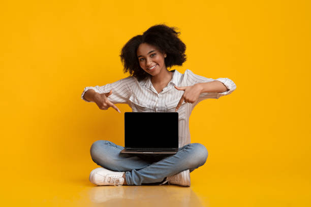 istock Afro woman pointing at laptop with blank screen on her laps 1209185848