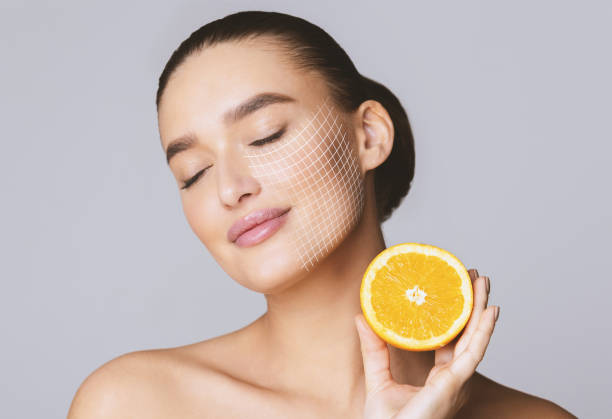 encantado joven bonita mujer con los ojos cerrados sosteniendo la mitad naranja - vitamin c fotografías e imágenes de stock