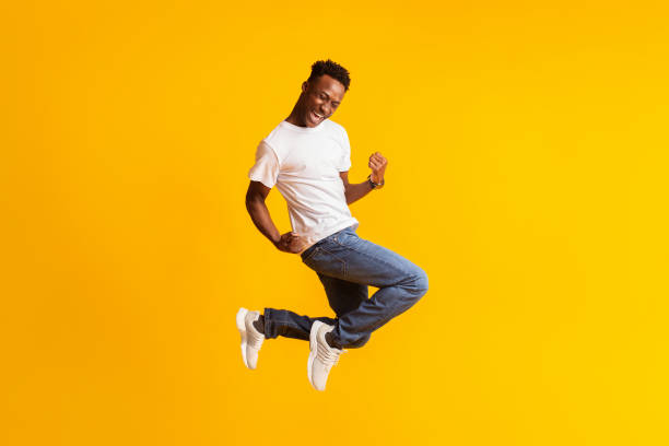 istock Happy excited young black man jumping over yellow 1209187337