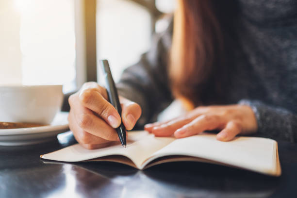 istock a woman writing on a blank notebook on the table 1209193966