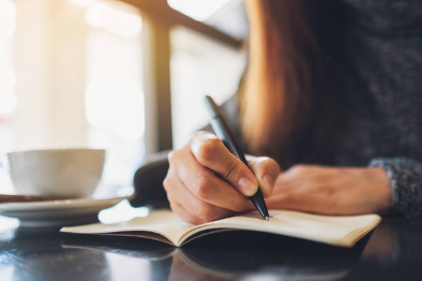 a woman writing on a blank notebook on the table