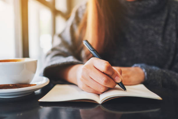 istock a woman writing on a blank notebook on the table 1209193968