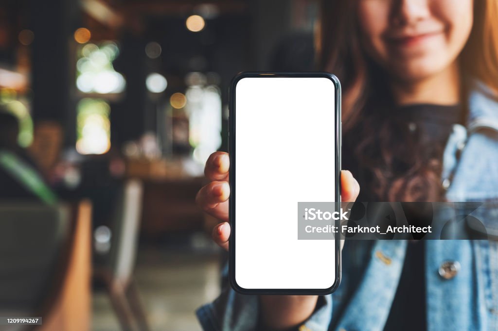 a woman holding and showing black mobile phone with blank white screen in cafe Mockup image of a woman holding and showing black mobile phone with blank white screen in cafe Mobile Phone Stock Photo