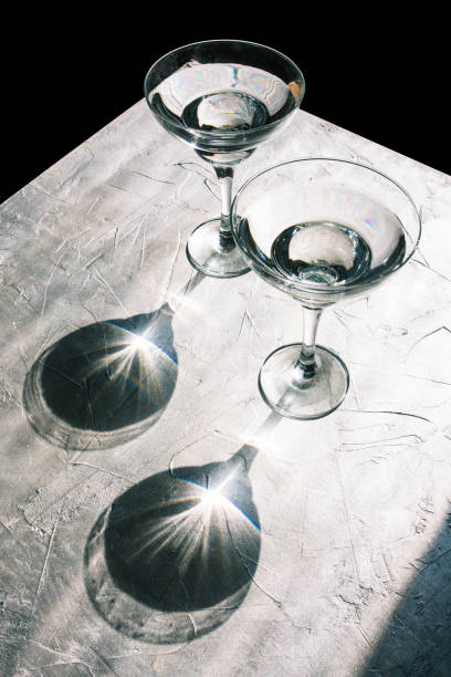 istock Sunlight shines on two cocktail glasses with a drink. Reflection from glass goblets on a silver background. 1209196053