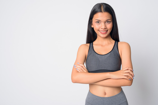 Studio shot of young beautiful Asian woman ready for gym against white background