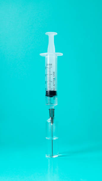 istock Syringe with a needle in an ampoule on a blue background. 1209199271