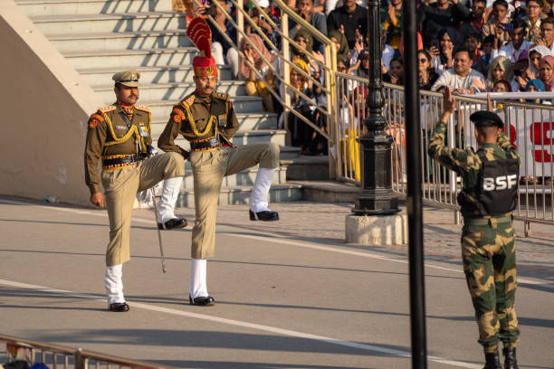 les forces de sécurité frontalières indiennes marchent vers la frontière de wagah et font des coups de pied élevés pendant la cérémonie de clôture avec le pakistan - closing ceremony photos et images de collection