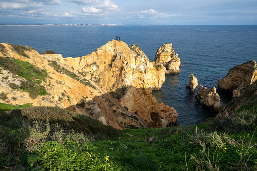 Lagos, Portugal - January 22, 2020: Thrillseeker tourists take photos with a phone on a very steep cliff in the Algarve, of scenic vistas
