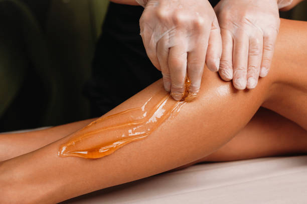 Close up photo of a sugaring on legs procedure done by a experienced specialist in spa Close up photo of a sugaring on legs procedure done by a experienced specialist in spa wax stock pictures, royalty-free photos & images