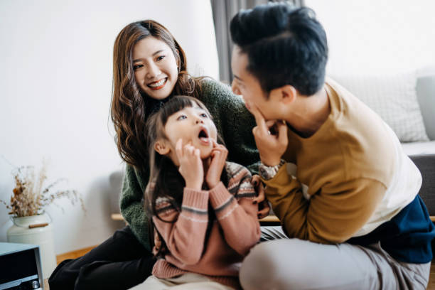 istock Young family having fun at home while father and daughter making silly faces together 1209205182
