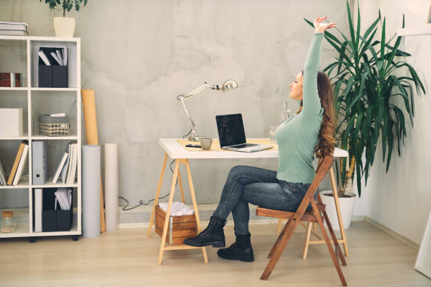 istock Young attractive female doing stretching exercises in modern home office. 1209208362