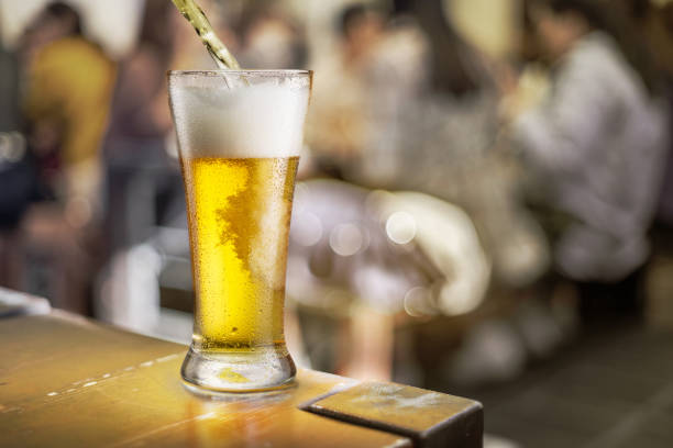 istock Pouring light beer into a glass at a counter in a pub. Behind the blurred pubs background. 1209208665